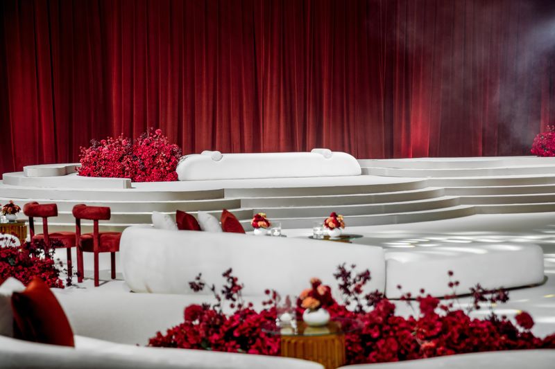 White lounges and red chairs around the stage, red roses and berries at the edge of the floor
